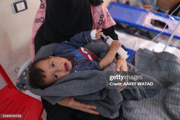 Woman carries her baby during treatment at a recently-opened medical center for Cholera cases in the Syrian town of Darkush, on the outskirts of the...