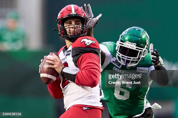 Jake Maier of the Calgary Stampeders looks for a receiver as A.C. Leonard of the Saskatchewan Roughriders tries to strip the ball in the first half...