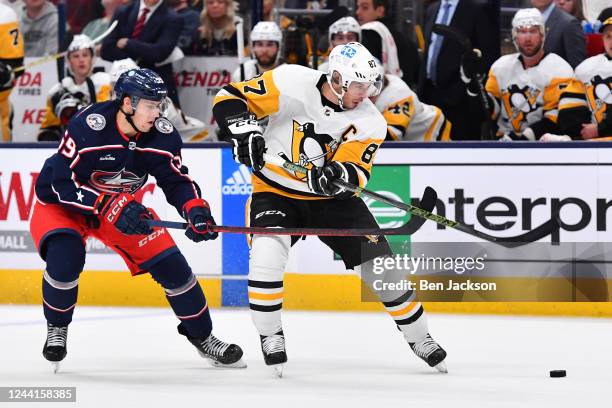 Sidney Crosby of the Pittsburgh Penguins and Yegor Chinakhov of the Columbus Blue Jackets battle for the puck during the second period of a game at...