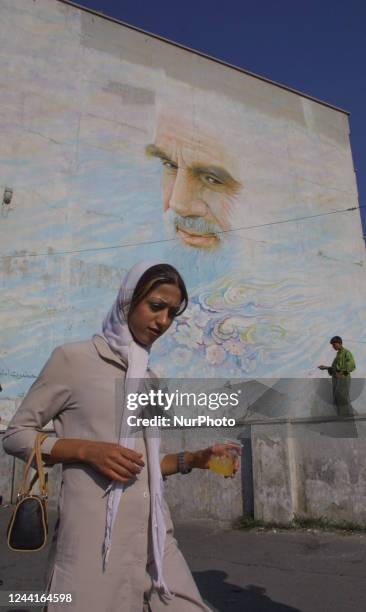 In this August 12, 2003 file photo, An Iranian young woman walks under a mural with a portrait of the founder of Irans Islamic Republic, Ayatollah...