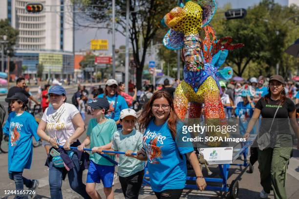 Family carries an Alebrije passing over Paseo de la Reforma during the Parade of Monumental Alebrijes. The 14th edition of the Monumental Alebrijes...