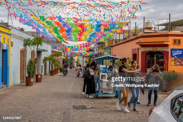 People getting ice cream from a street vendor in the with Papel picado decorated streets of Barrio de Jalatlaco, in Oaxaca City, Mexico.