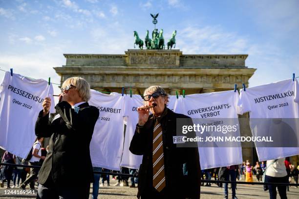 Performers representing Qatar and world football's governing body FIFA stand in front of T-shirts inscribed with the words : "Slave Labour",...