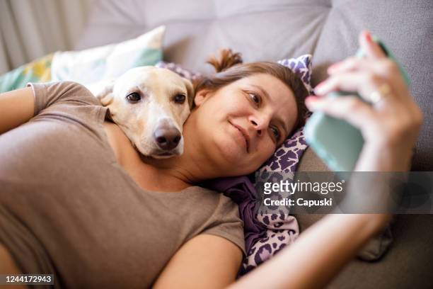 woman and dog watching videos on phone - one woman only videos stock pictures, royalty-free photos & images