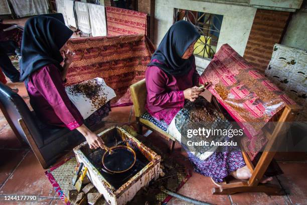 Batik craftswomen applies melted wax using a spouted tool called a canting as make traditional Indonesian batik at the Batik Semarang 16 workshop on...