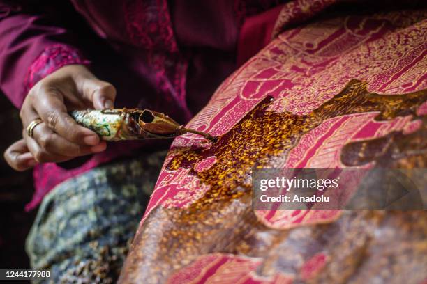 Batik craftswoman applies melted wax using a spouted tool called a canting as make traditional Indonesian batik at the Batik Semarang 16 workshop on...
