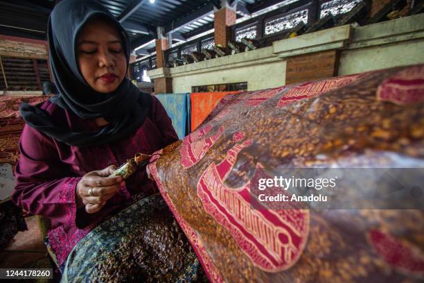 Batik craftswoman applies melted wax using a spouted tool called a canting as make traditional Indonesian batik at the Batik Semarang 16 workshop on...