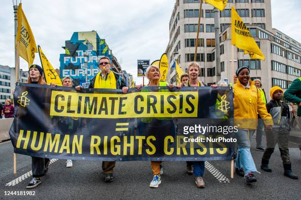 People are holding a banner from Amnesty International, during a massive climate demonstration organized in Brussels, on October 23rd, 2022.