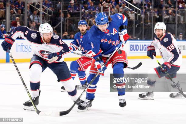 Artemi Panarin of the New York Rangers skates with the puck against Vladislav Gavrikov of the Columbus Blue Jackets at Madison Square Garden on...