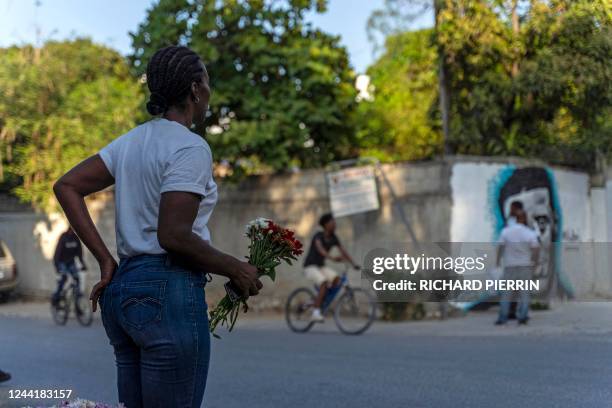 Woman carries flowers to place at a mural in honor of late Haitian musician Michael Mikaben Benjamin in Port-au-Prince on October 23, 2022. - Mikaben...