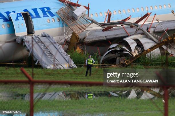 Member of security looks at the plane of Korean Air flight KE631 with its belly lying on the runway at the airport in Cebu City, central Philippines...