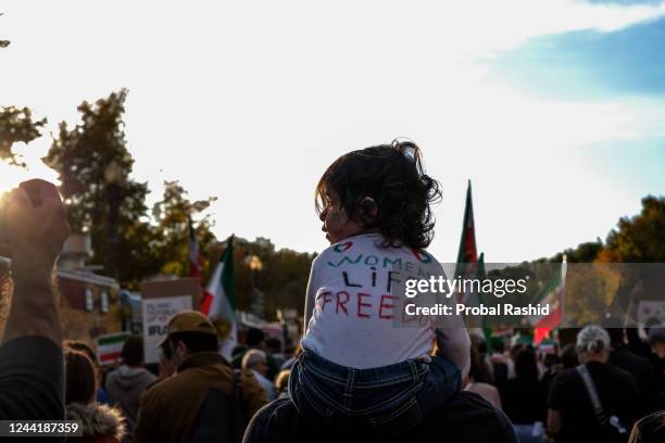 Baby girl wearing a T-shirt Women Life Freedom written on it, sitting on her father's shoulders is seen during a march in support of the women of...