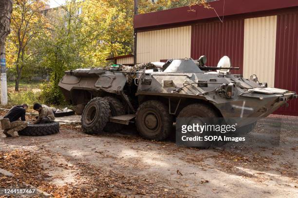 Ukrainian soldiers change the tires on an APC, an armored personal carrier of the Ukrainian army, near a damaged building after a Russian shelling in...