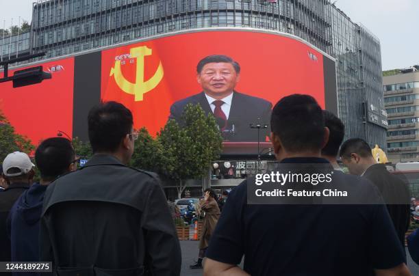 Pedestrians stop at a crossing where a giant screen televising a speech by Xi Jinping at closing ceremony of the 20th National Congress of the...