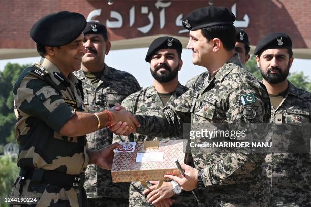 Indian Border Security Force commandant Jasbir Singh presents sweets to Pakistan's Rangers wing commander Aamir on the occasion of the Hindu festival...