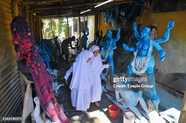 Two curious Muslim students looking over sculptures of the Hindu goddess Kali at Dariya Para, Sylhet, on October 21, 2022.