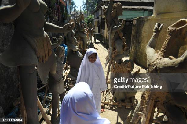 Two curious Muslim students looking over sculptures of the Hindu goddess Kali at Dariya Para, Sylhet, on October 21, 2022.