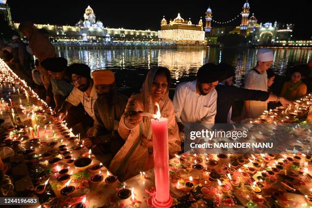 Devotees light candles and earthen lamps as they pay respect at the illuminated Golden Temple on the occasion of Bandi Chhor Divas, a Sikh festival...