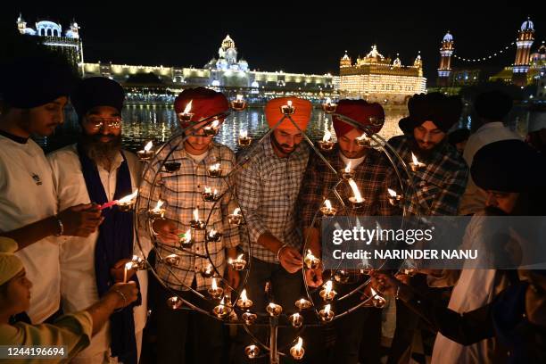 Devotees light lamps as they pay respect at the illuminated Golden Temple on the occasion of Bandi Chhor Divas, a Sikh festival coinciding with...