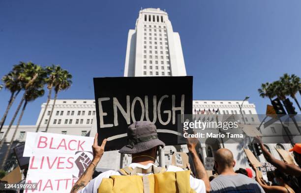 Protester holds a sign outside City Hall reading 'Enough' during a peaceful demonstration over George Floyd’s death on June 3, 2020 in Los Angeles,...