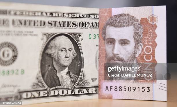 Picture of a one US dollar bill next to a Colombian five thousand peso bill taken in Bogota, on October 24, 2022. - Colombia, like other countries...