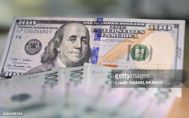 Picture of a one hundred US dollar bill next to Colombian one hundred thousand peso bills taken in Bogota, on October 24, 2022. - Colombia, like...