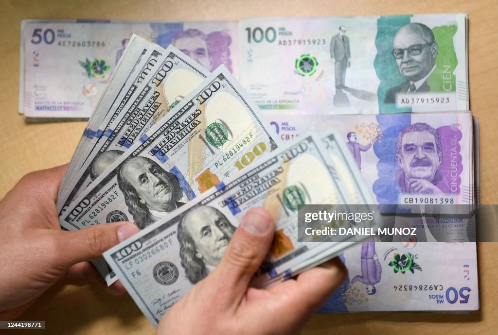 A man counts one hundred US dollar bills as Colombian peso bills