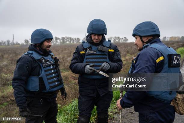 Members of a mine clearance team view a Russian bayonet that was found during a search for roadside for mines and improvised explosive devices on...