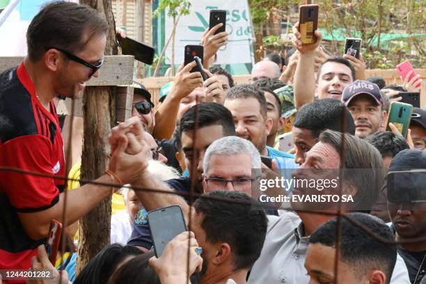 Brazilian President and re-election candidate Jair Bolsonaro greets a supporter during a campaign rally at the Nova Jerusalem settlement, 40 km from...