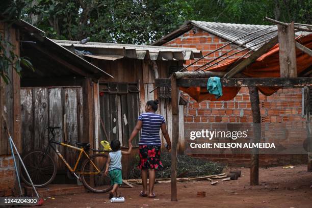 Woman and her child walk at the Tekoha Marangatu Guarani indigenous village in the municipality of Guaira, Parana state, Brazil, on October 13, 2022....