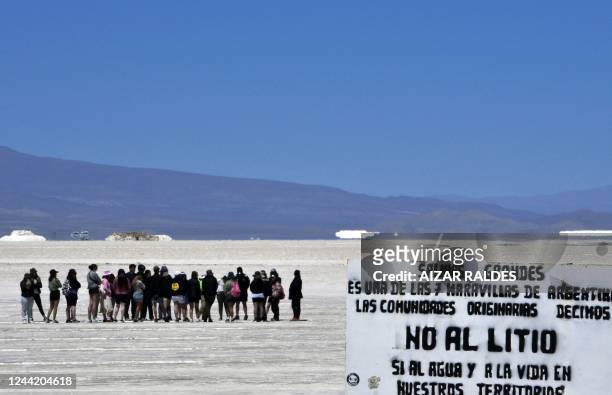 Sign against the exploitation of lithium is seen as tourists visit the Salinas Grandes salt flat, shared by the Argentine northern provinces of Salta...