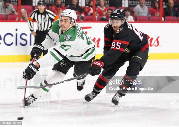 Mason Marchment of the Dallas Stars shoots the puck while falling as Jake Sanderson of the Ottawa Senators reaches in from behind at Canadian Tire...