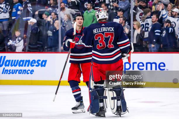 Goaltender Connor Hellebuyck of the Winnipeg Jets gets congratulated by teammate Mark Scheifele following a 4-0 shutout victory over the St. Louis...