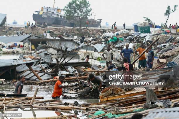 Residents search for their belongings amid the debis of their collapsed huts after the cyclone Sitrang hits in Chittagong on October 25, 2022. - At...