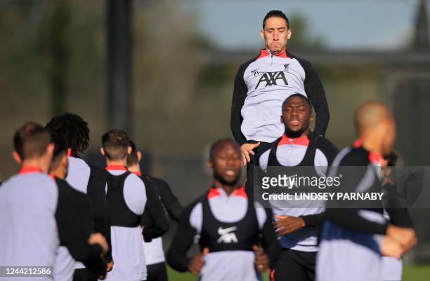 Liverpool's Greek defender Kostas Tsimikas jumps above teammates as he attends a team training session at the AXA Training Centre in Liverpool,...