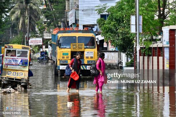 Women wade through a waterlogged street following cyclone Sitrang, in Barisal on October 25, 2022.