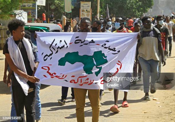 Demonstrator holds up a banner depicting a map of the countries of the Arab League with the Arabic slogans "Unity - Freedom - Socialism" and "No...