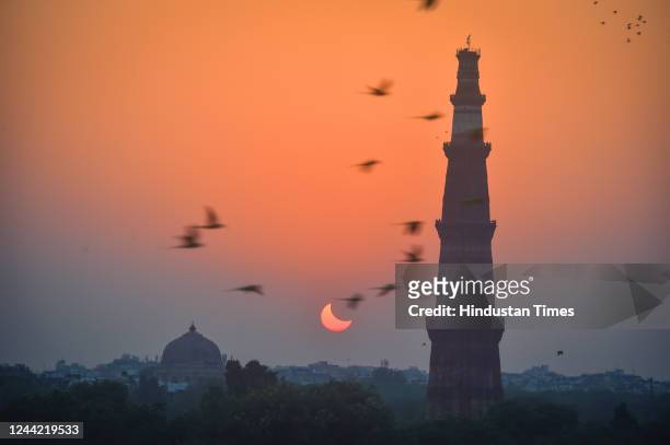View of a partial solar eclipse next to the Qutub Minar seen from Mehruli, on October 25, 2022 in New Delhi, India. The partial solar eclipse or...