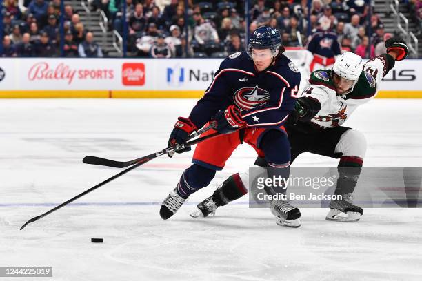 Andrew Peeke of the Columbus Blue Jackets and Shayne Gostisbehere of the Arizona Coyotes battle for the puck during the first period of a game at...