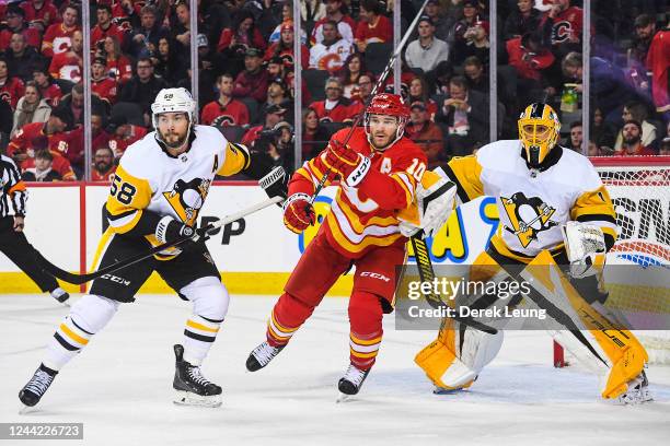 Jonathan Huberdeau of the Calgary Flames looks for an opportunity against Kristopher Letang and Casey DeSmith of the Pittsburgh Penguins during the...