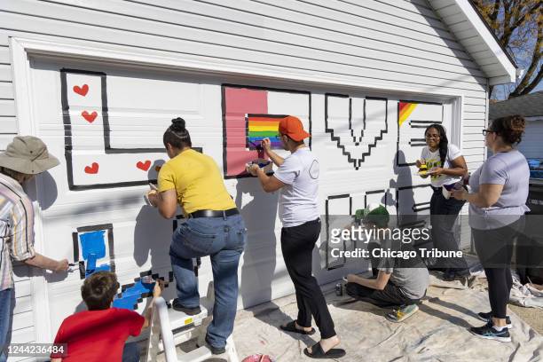Miembros de la comunidad y policÃ­as de Chicago ayudan a Erica Hungerford y Peter Charnley a pintar su garaje de Jefferson Park el domingo 23 de...