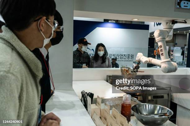 Visitors look at a robot cooking fried chicken during the event. Robotworld 2022 is held at Kintex in Goyang City, Gyeonggi Province. About 600...