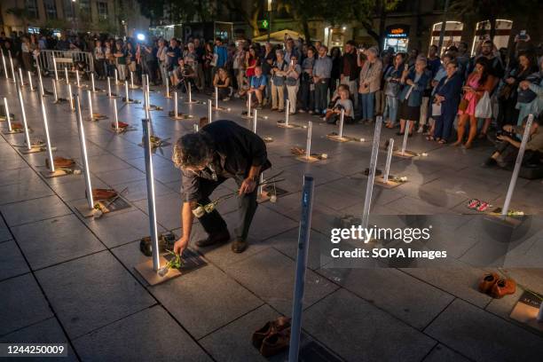 Man seen laying white roses on the names of homeless people who died during 2022, some of them on the streets. The social entity Fundación Arrels has...