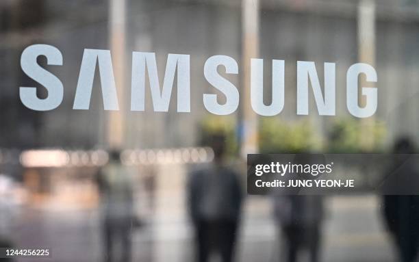 People walk past the Samsung logo displayed on a glass door at the company's Seocho building in Seoul on October 27, 2022. - South Korean tech giant...