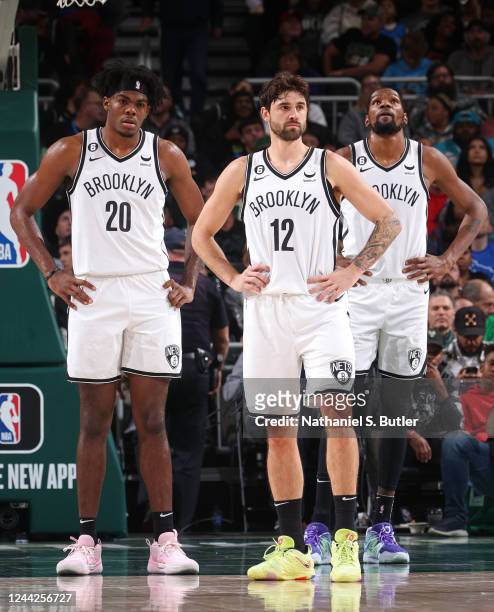 Day'Ron Sharpe, Joe Harris and Kevin Durant of the Brooklyn Nets stand on the court against the Milwaukee Bucks on October 26, 2022 at the Fiserv...