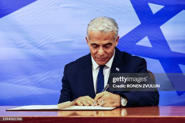 Israeli Prime Minister Yair Lapid signs the US-brokered deal setting a maritime border between Israel and Lebanon, at the Prime Minister's office in...