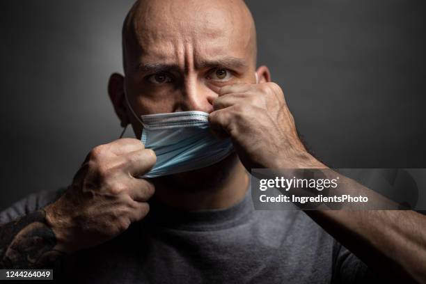 man rips off a protective mask from his face. - tear face stock pictures, royalty-free photos & images