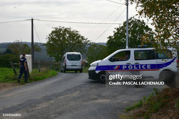Police officer walks as a hearse passes by a farm in Beynat, southwestern France, on October 27 after police found a body during the search for...