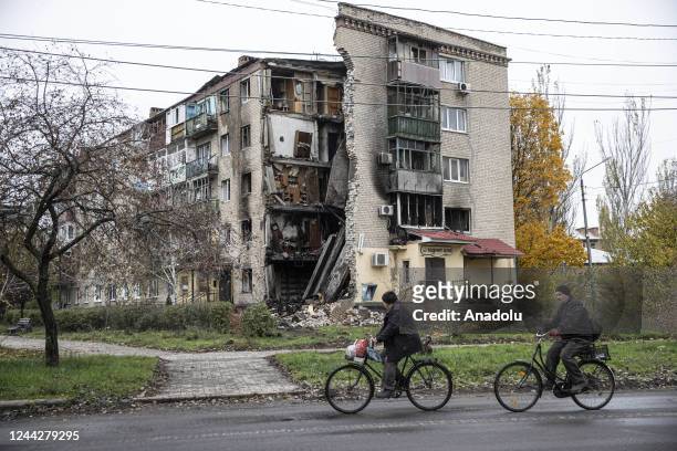 Ukrainian civilians ride their bikes near partially collapsed buildings in Bakhmut city, where the most violent conflicts take place in Ukraine on...