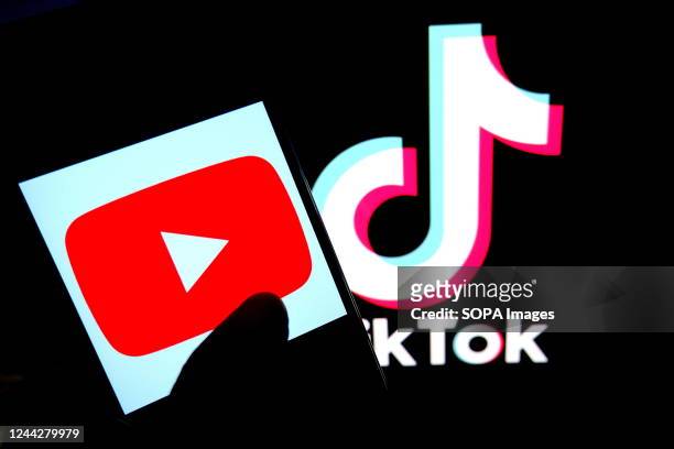 In this photo illustration, a Youtube logo is displayed on a smartphone with a Tiktok logo in the background.